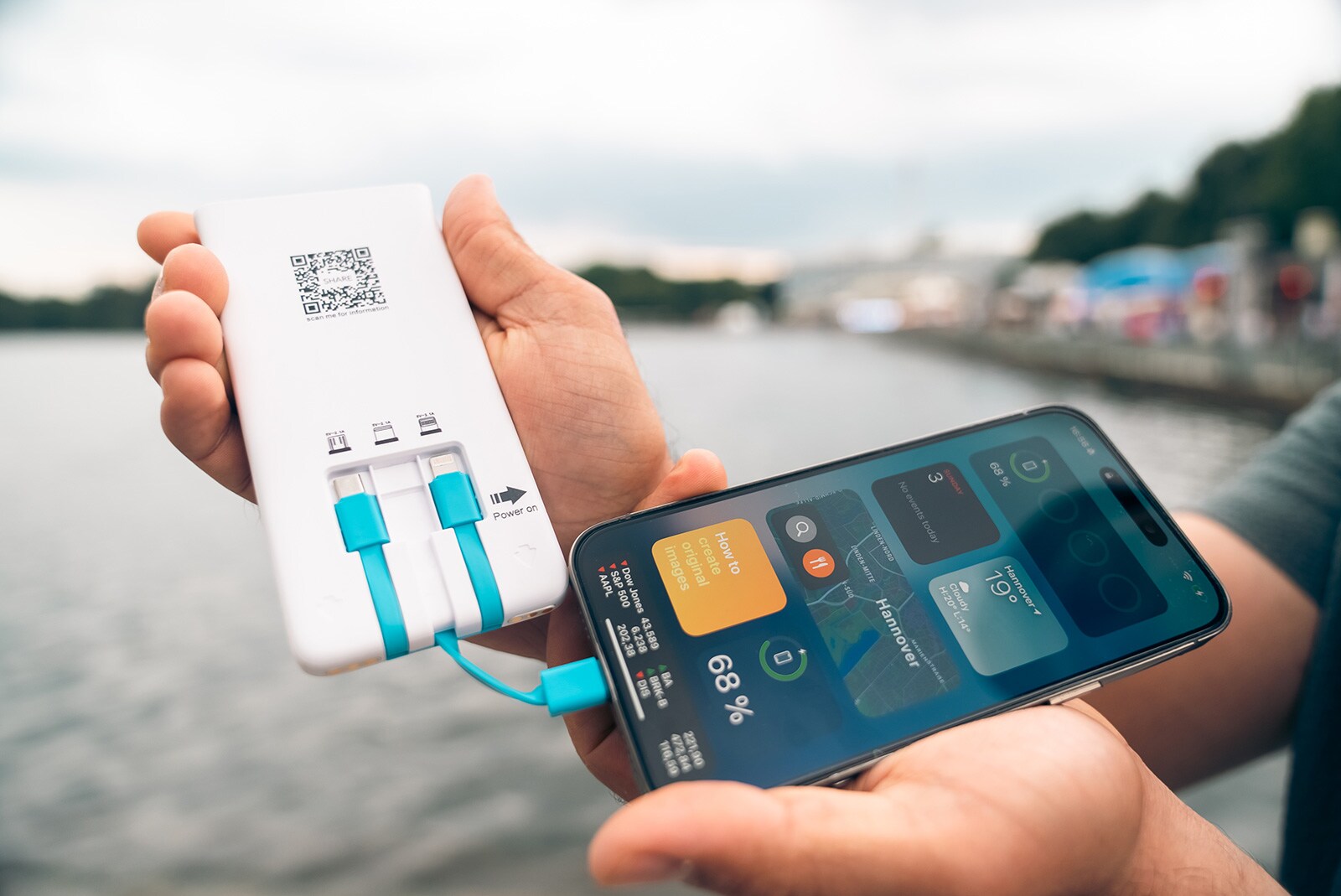 A man holds a SHARE power bank in his hands, which is connected to his smartphone.