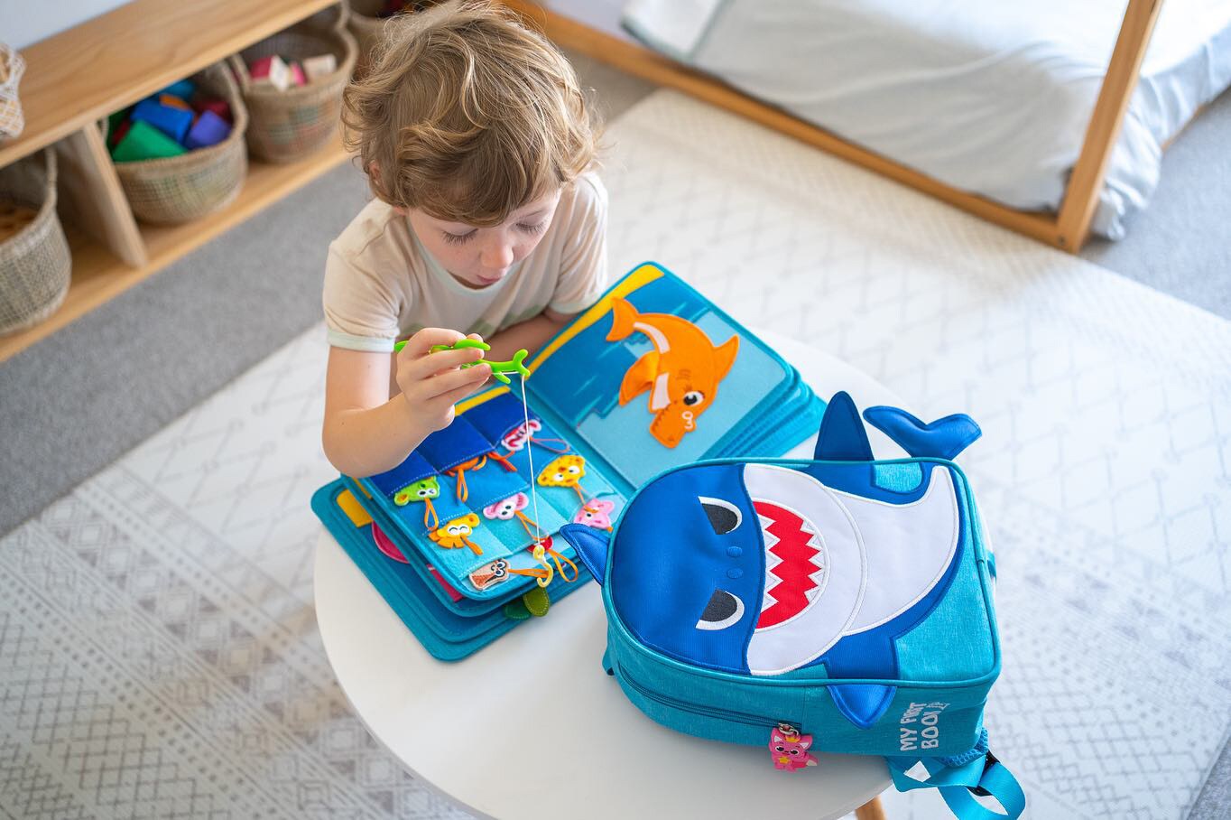 Ein kleiner Junge sitzt an einem Kindertisch und schaut sich ein interaktives Bilderbuch an