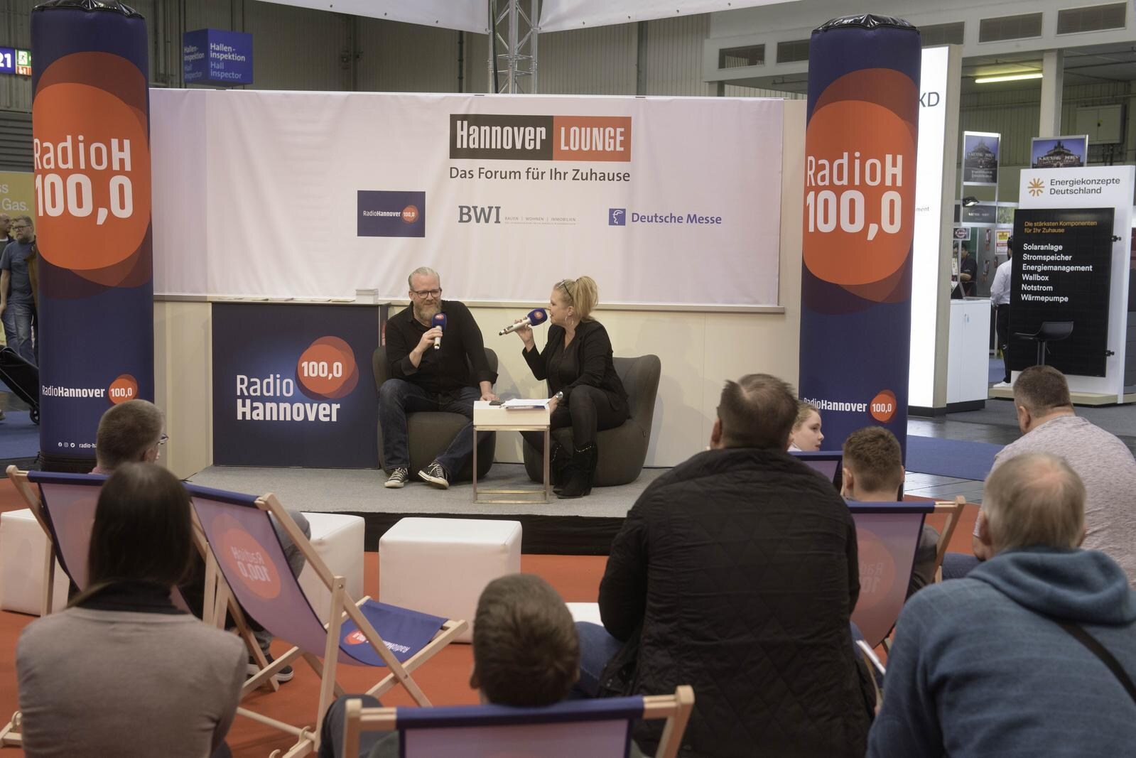 Auf der Bühne der Hannover Lounge von Radio H sitzen ein Mann und eine Frau und unterhalten sich vor Publikum
