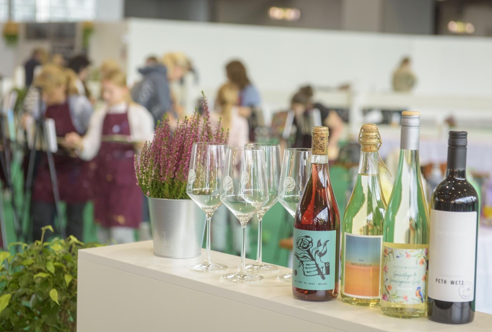 Wine bottles and glasses are in the foreground, while visitors can be seen painting at easels in the background. All part of the Uncorked Art workshops.