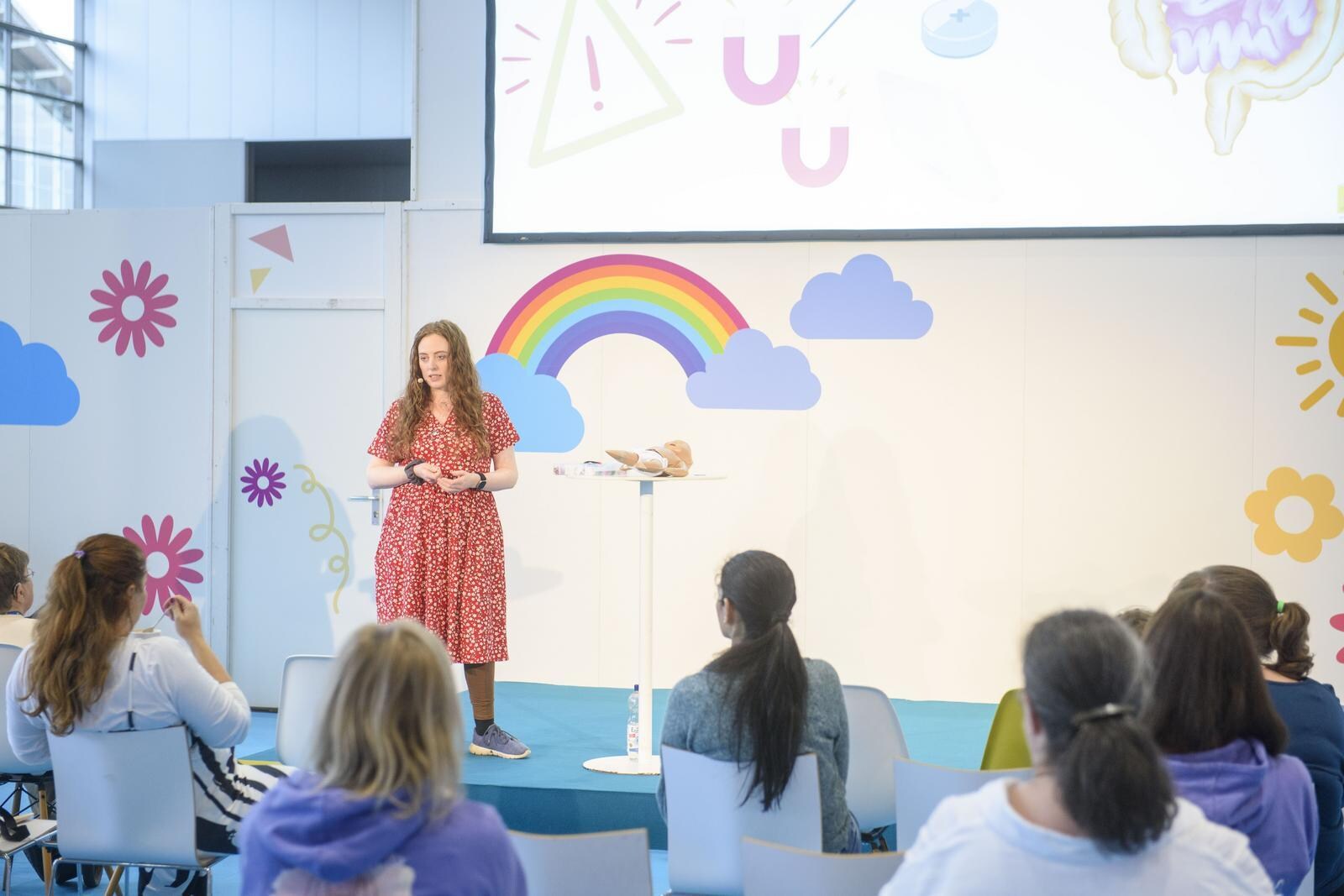 A woman stands on the infalino stage and gives a presentation to an audience.